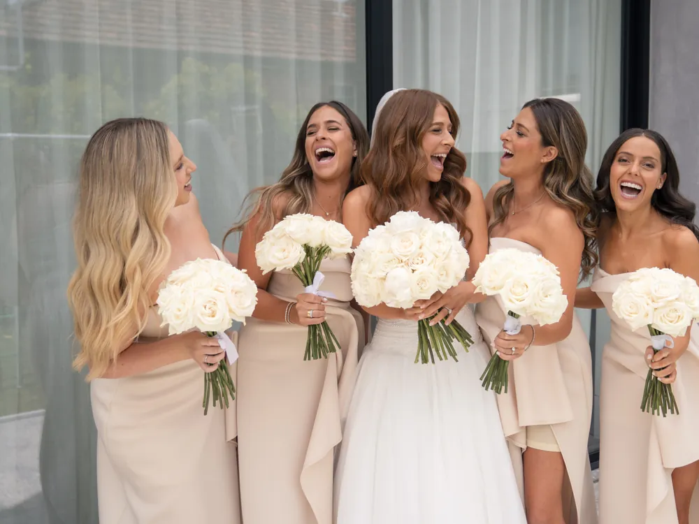A bride laughing with her four bridesmaids, every one of them styled