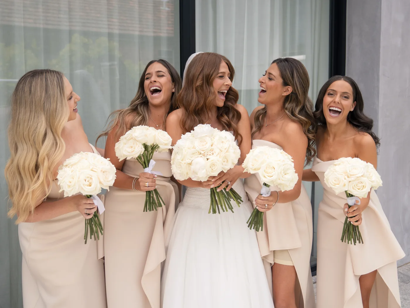 A bride laughing with her four bridesmaids, every one of them styled