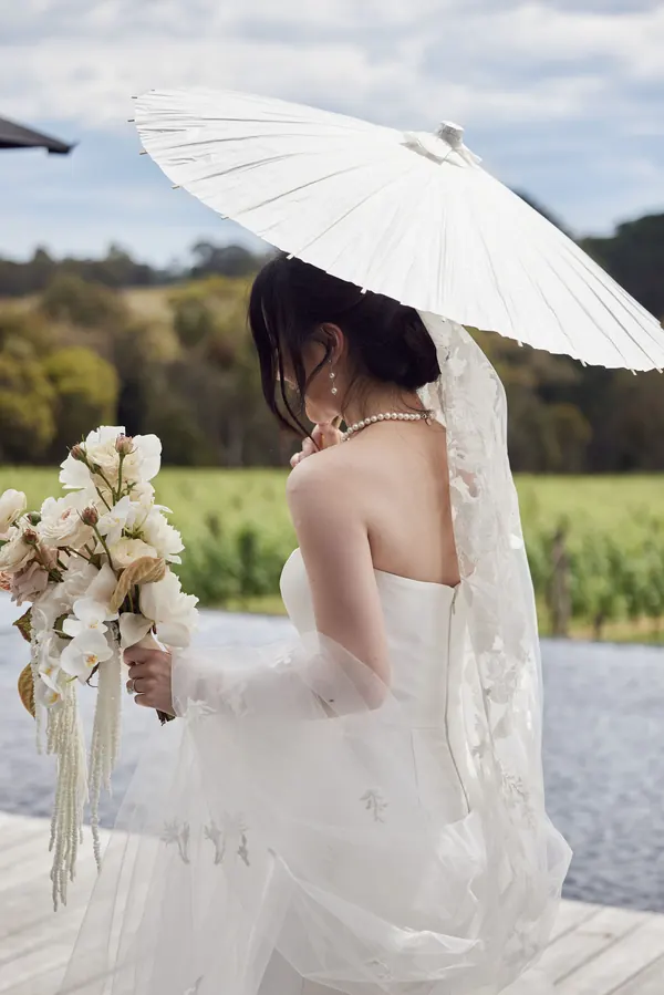 Under a white parasol at a vineyard, a low chignon and a pearl necklace