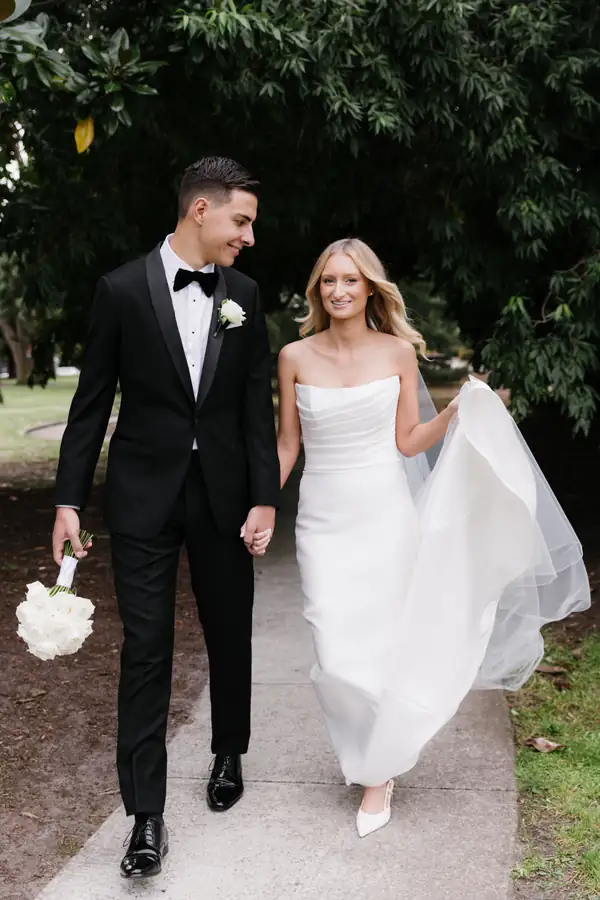 Bride and groom walking a garden path, her hair down under a soft veil