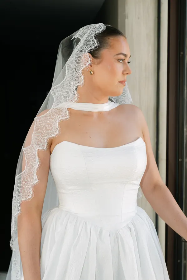 A lace-edged veil over a sleek dark style, seen in profile