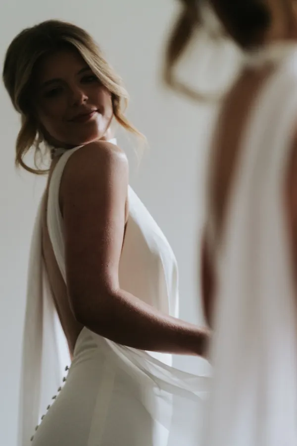 Blonde hair falling over a bare shoulder above a cowl back