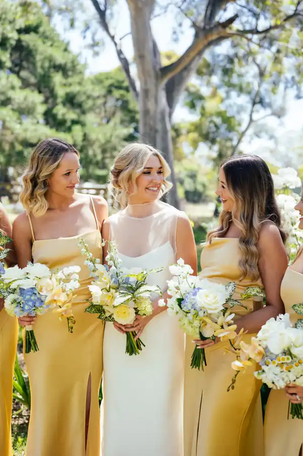 The bridesmaids in yellow with their bouquets, hair down and styled